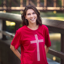 Load image into Gallery viewer, Female model wearing red t-shirt with large white Christian cross photographed outdoors with bokeh