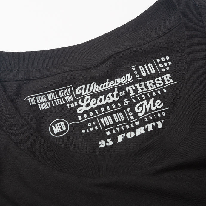 Close up of Plain black t shirt with Matthew 25:40 printed as the tag