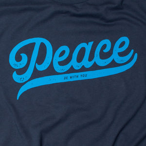 Close up of Navy blue t shirt with "Peace be with you"  in script on light blue on the front