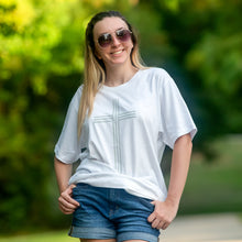 Load image into Gallery viewer, Model wearing white Christian cross t-shirt, denim shorts and sunglasses photographed outside with soft green background