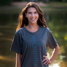 Load image into Gallery viewer, Model photographed outside during the magic hour wearing a gray t shirt with a Christian cross of circles.
