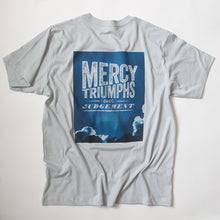 Load image into Gallery viewer, James 2:13, Mercy triumphs over judgement, on blue sky photo on light grey t shirt