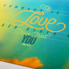 Load image into Gallery viewer, Close up of John 15:12 in modern graphics on sunset background