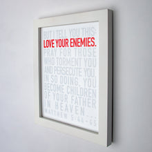 Load image into Gallery viewer, Matthew 5:44-45, Love your enemies in red, other type in gray, on fine art paper in white frame.