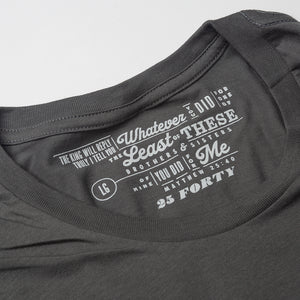 Close up photo of Matthew 25:40 printed in light grey as the tag for a charcoal t shirt