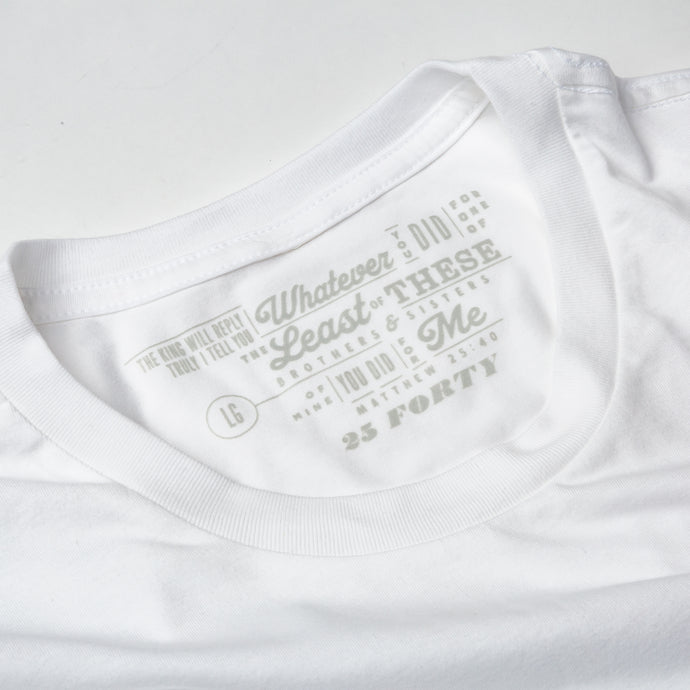 Studio close up photo of collar of white t shirt on white background with Matthew 25:40 printed as the tag