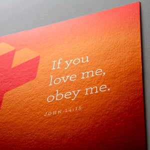 Close up of John 14:15, "If you love me, obey me." Printed on orange cross photo.